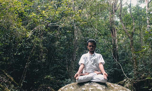 man meditating in a forest