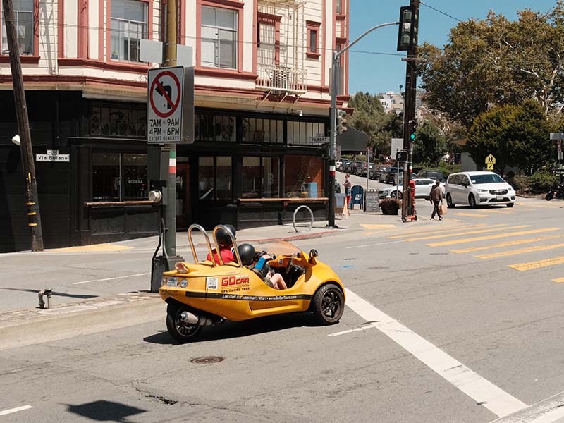 two people navigate SF city streets in a bright yellow GoCar